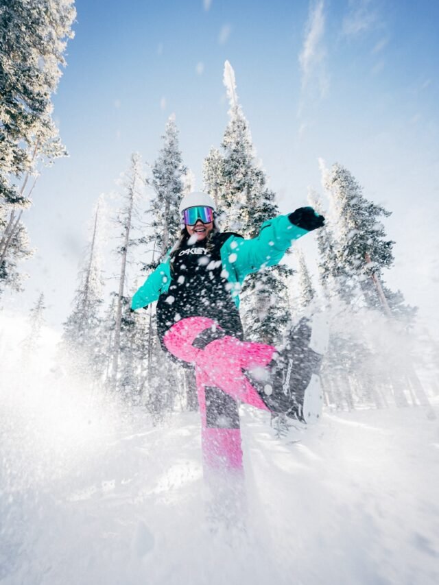 person in blue jacket and pink pants riding on snowboard during daytime