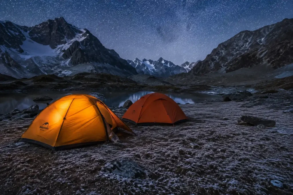 Tents pitched at high-altitude campsite on a Kashmir trek with snow-dusted peaks in the background at dusk