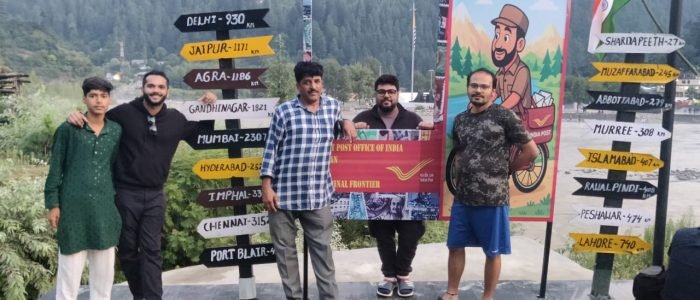 A group of tourists from Travel My Kashmir posing for a photograph at the post office in Keran Valley, Kupwara.