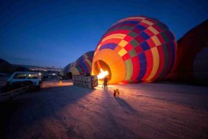 person standing near multicolored hot air balloon during night time in Srinagar, hot air balloon srinagar booking