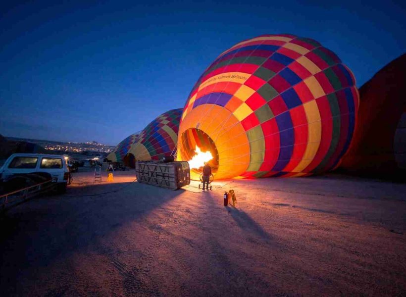 person standing near multicolored hot air balloon during night time in Srinagar, hot air balloon srinagar booking